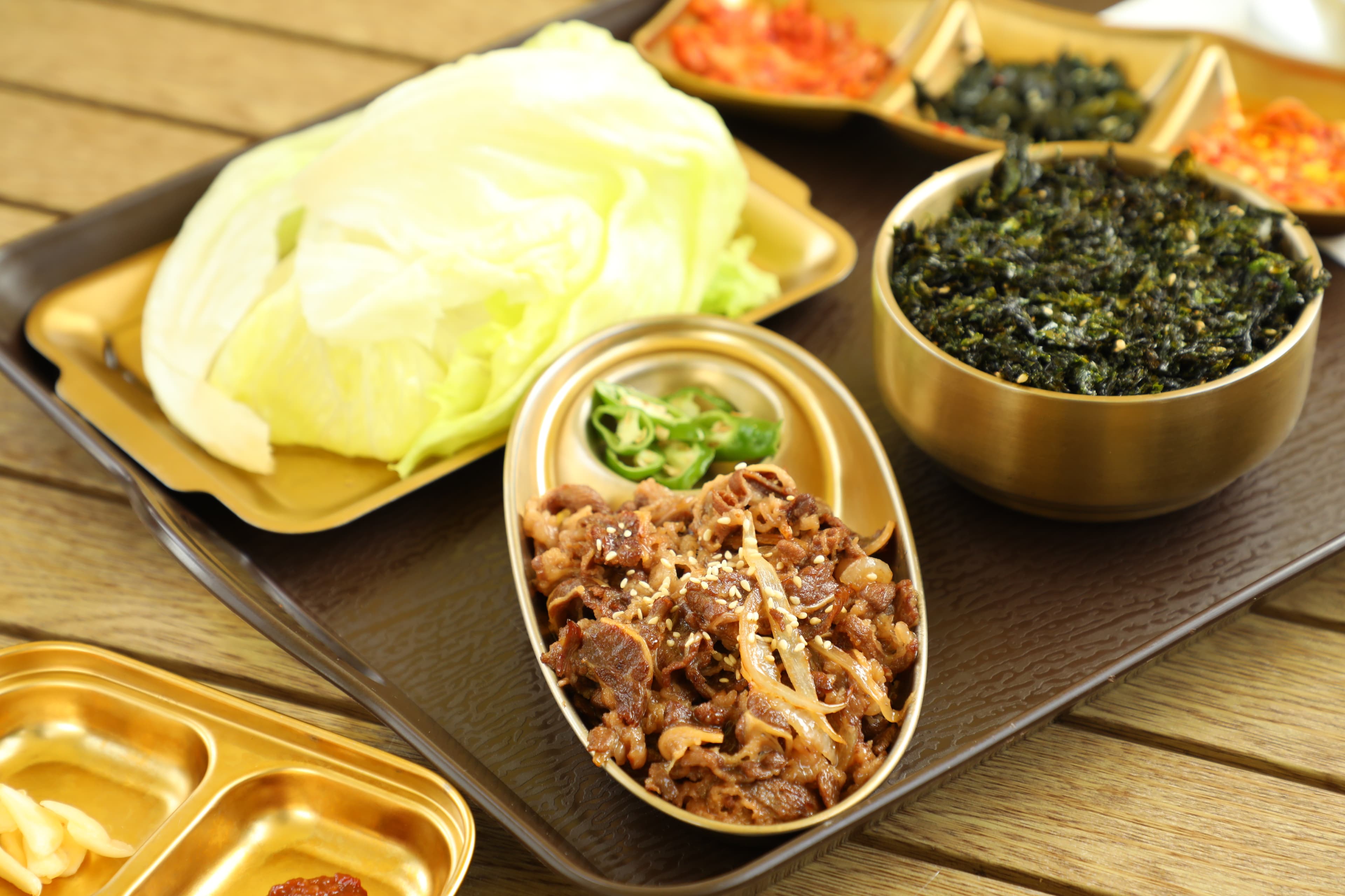 「韓式生菜包牛肉定食」用生菜包上鮮嫩牛肉、泡菜與海苔碎，一口吃下非常清爽。（340元／份）