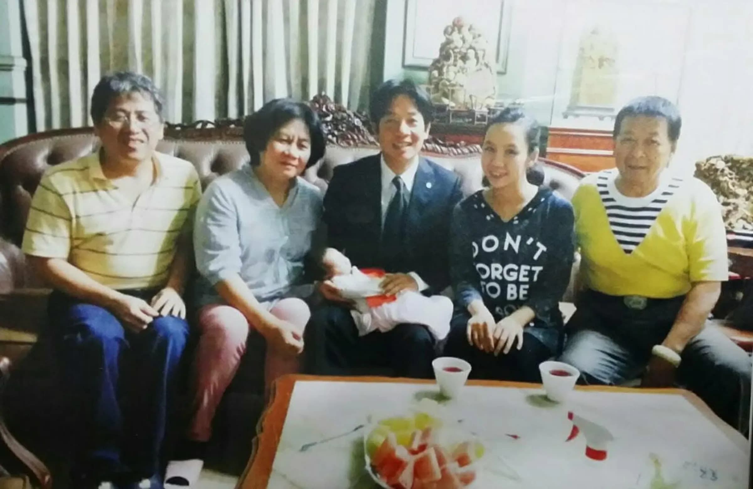 姜厚任女友童芯父親、綠營輔選大佬陳宏明（右起）、童芯、賴清德、陳苡孋的媽媽以及通靈老師。賴清德手中抱著童芯的孩子，照片推估拍攝於賴清德擔任台南市長任內。（《鏡報》提供）