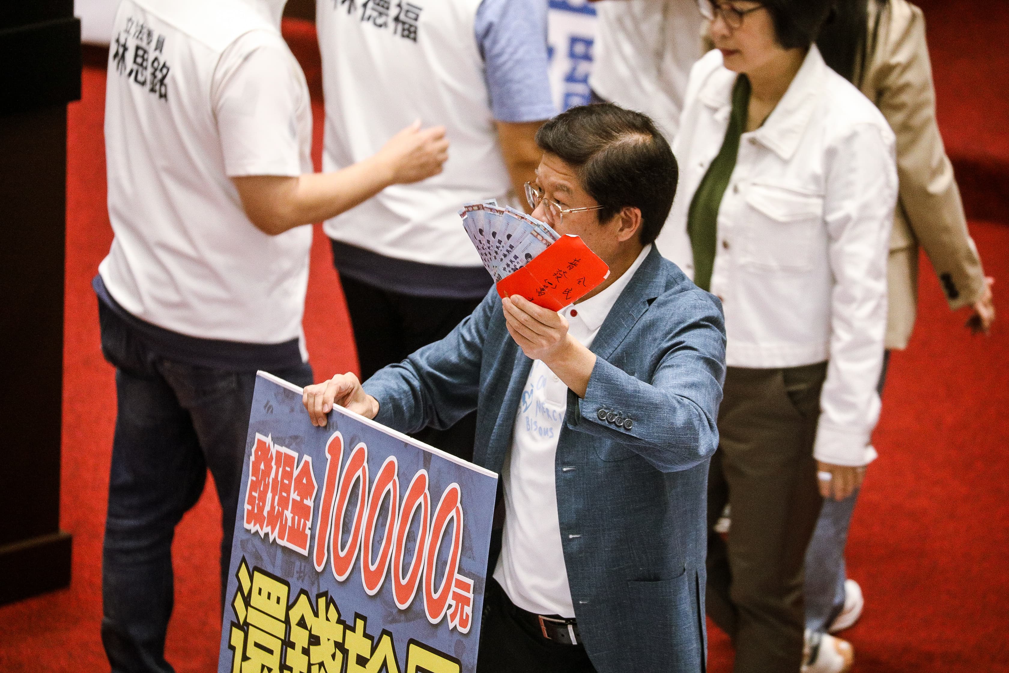 國民黨立委羅明才上個月在議場高舉10張1千元，說這就是1萬元，主張要普發1萬元「還錢於民」。（鏡報鄒保祥攝）