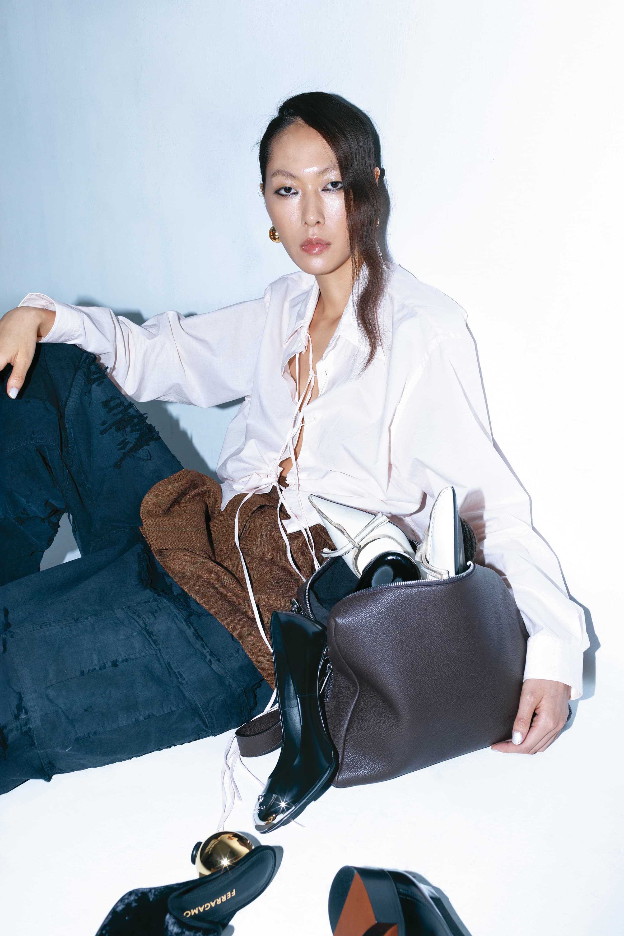 棕灰色郵差包 NT$106,500 by FENDI、粉色繫帶襯衫 NT$60,000 by PRADA、棕色短裙 NT$77,000 by PRADA、黑色丹寧長褲 價格店洽 by BALENCIAGA、（上）米白色尖頭高跟鞋 NT$51,000 by PRADA、（中）銀色金屬拼接高跟鞋 價格店洽 by VERSACE、（下）Tasha金色跟穆勒鞋 NT$37,900 by FERRAGAMO、金色耳環 NT$24,200 by FENDI