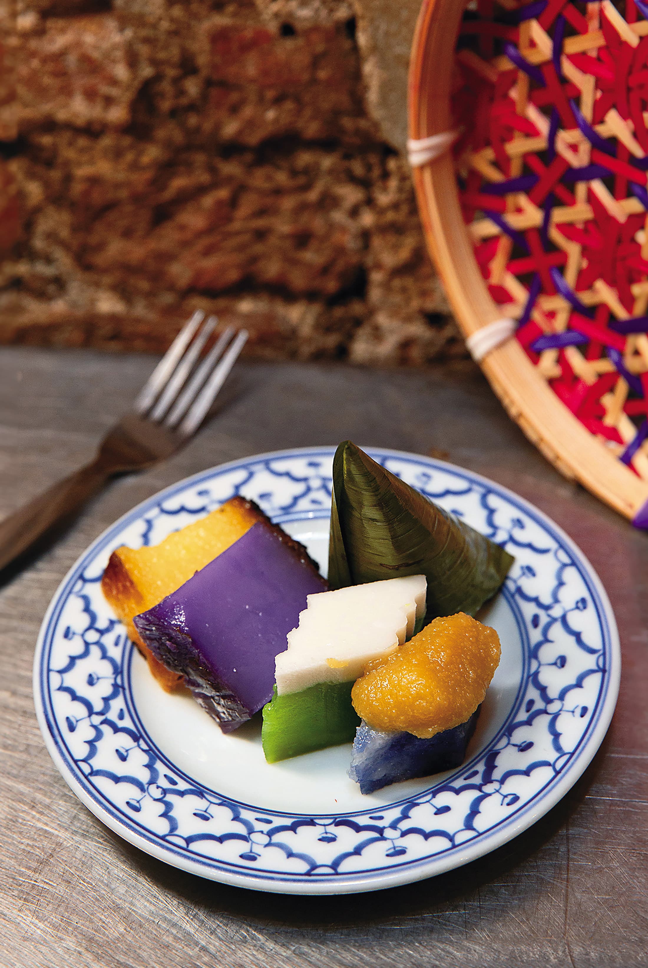 在店內能品嘗到「三角椰絲糕（Kueh Koci）」（後）與「蝶豆花咖椰糕（Pulut Tai Tai）」（前右起）「香蘭達蘭糕（Kueh Talam）」「紫薯米糕（Kueh Bengka Purple）」「木薯蛋糕（Kueh Bengka Ubi）」等多種娘惹糕點。（馬幣0.6～2.2元／份，約NT$5～17）