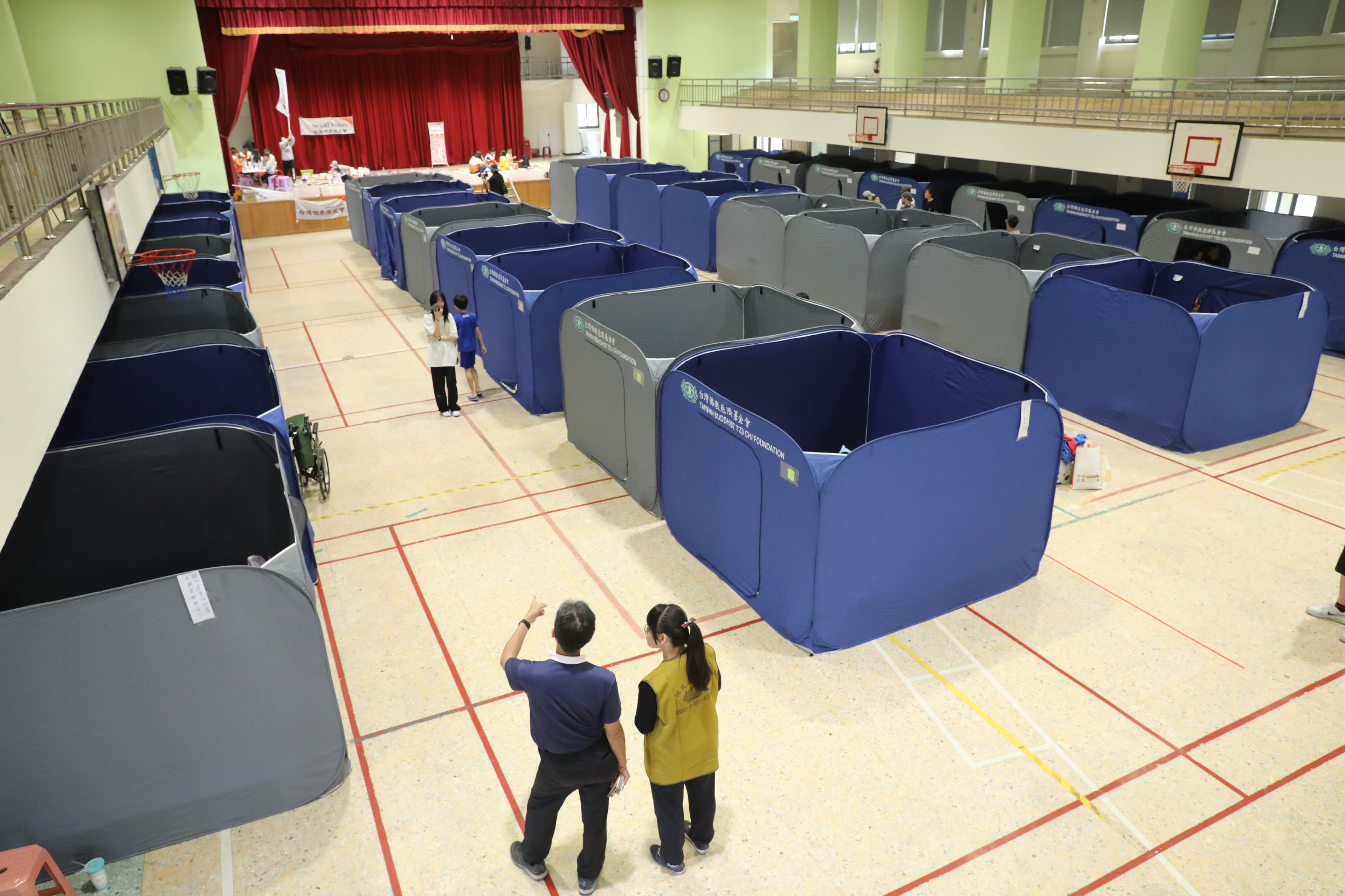 慈濟基金會在國小體育館架設「淨斯福慧環保隔屏」，提供災民隱私空間。