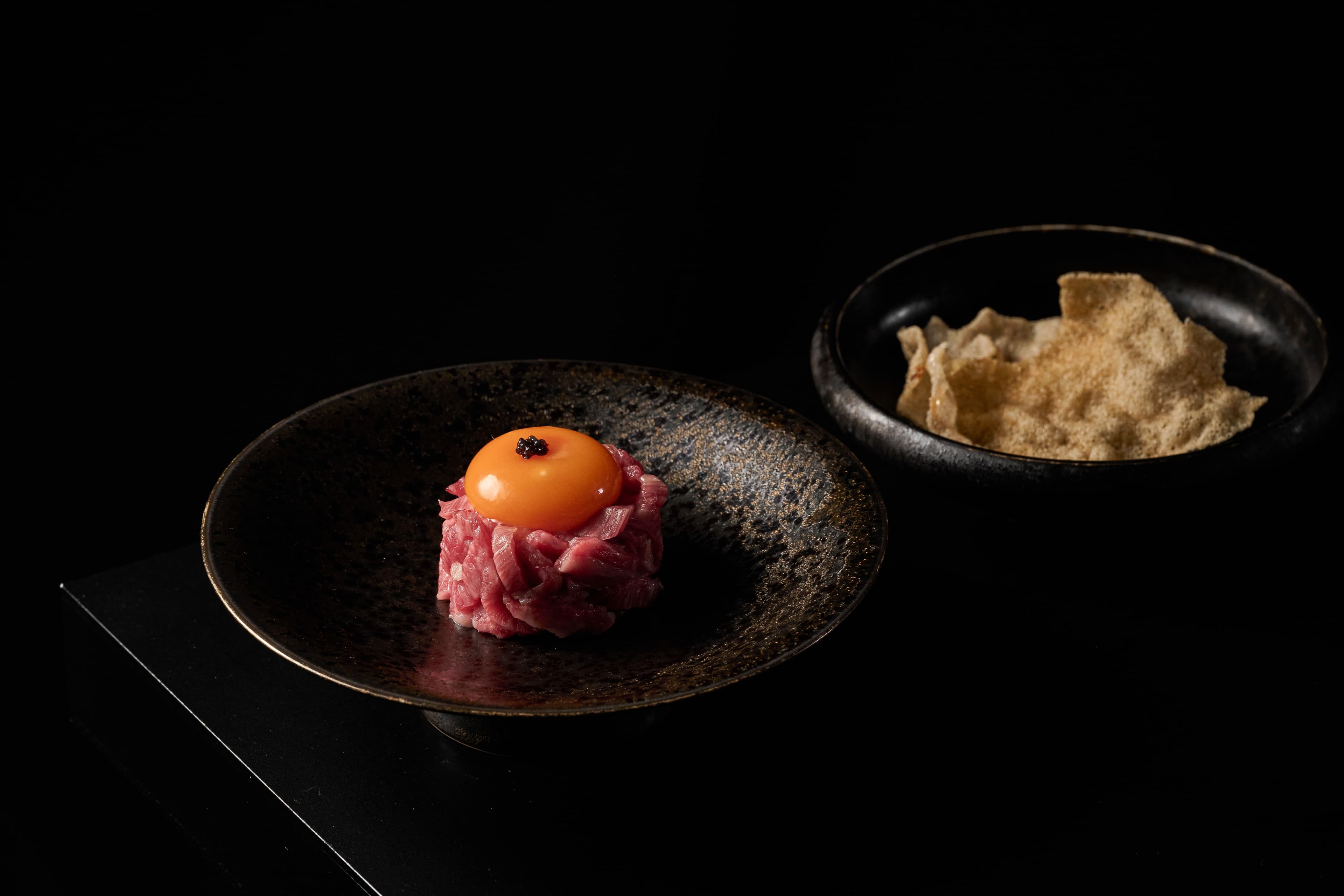 燒肉風間FEAST套餐中的前菜「A5日本和牛韃靼、魚子、櫻花蝦餅」取日本A5和牛的肩胛部位，手切條狀後調和秘製燒肉醬，拌入飽滿溫潤生蛋黃及魚子。（燒肉風間提供）