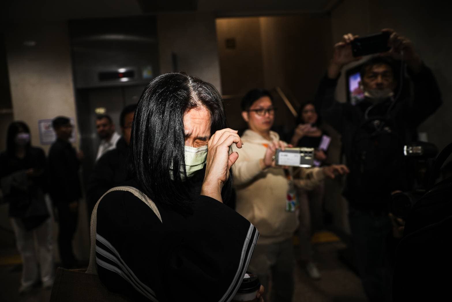 李文娟遭傳喚到案，面對鏡頭皺眉閉眼。