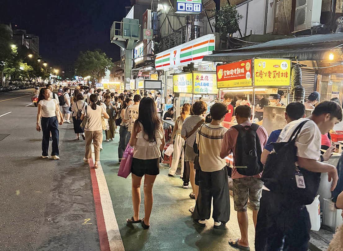 士林夜市攤商占用人行道做生意，造成人車爭道景象，但市府將其視為特殊文化免罰，引發議論。（讀者提供）