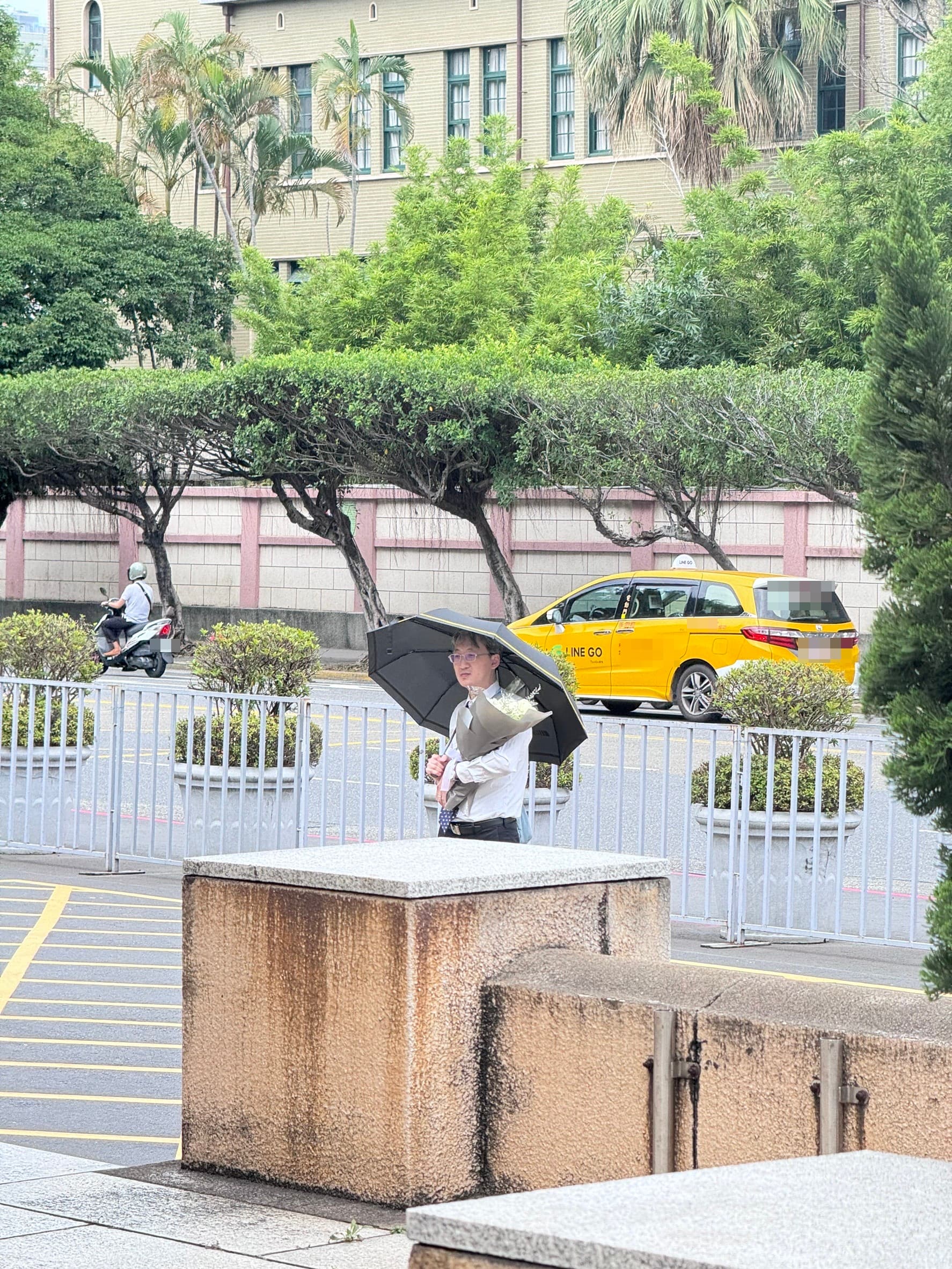 基隆地院法官李岳今現身司法院正門口，手捧白花、撐著黑傘，預計他將會在這站上一天。（本刊資料照）