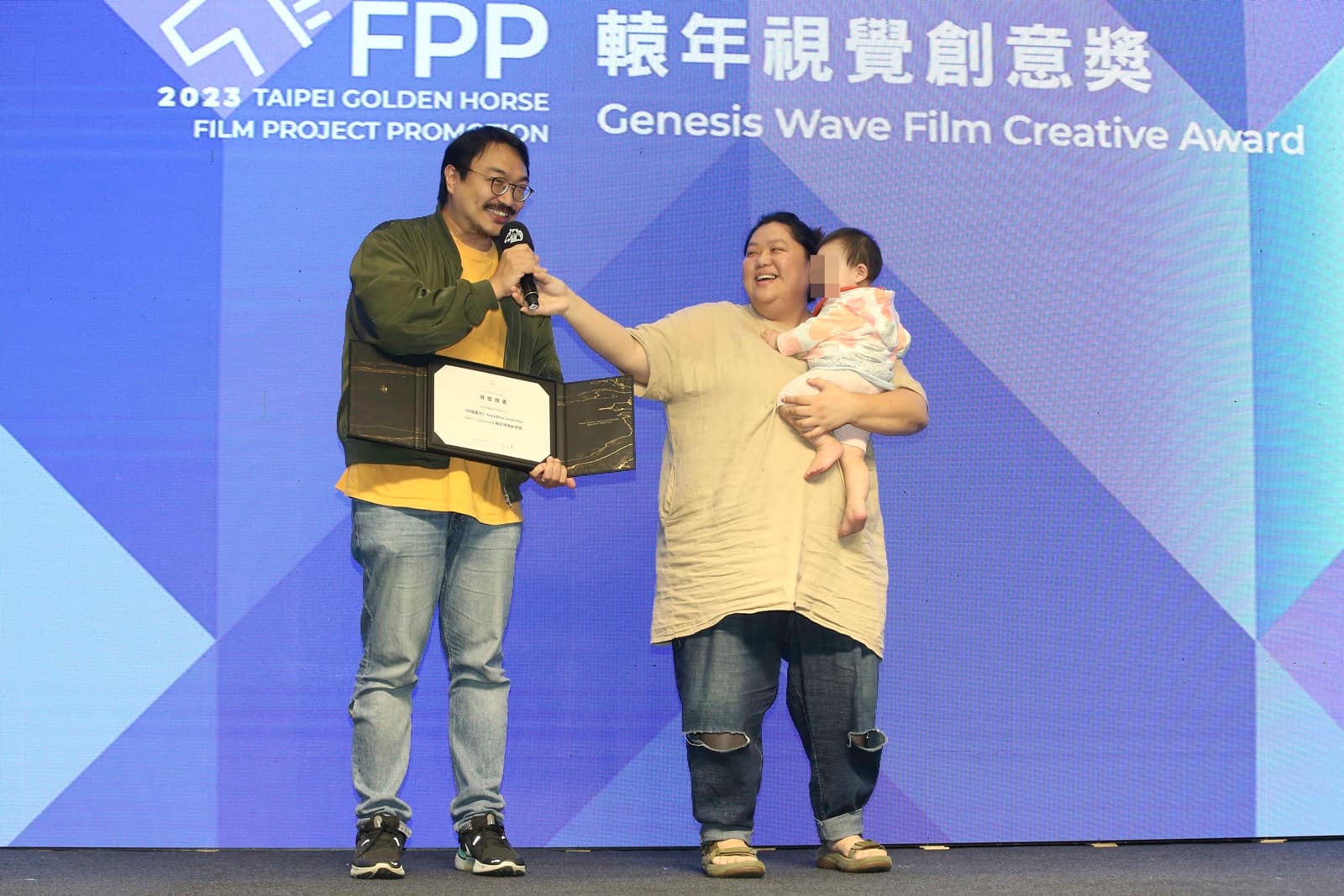 女星蔡嘉茵（右）抱著女兒，與劇場導演老公樊宗錡（左）一起代表《阿嬤愛你》上台領獎。