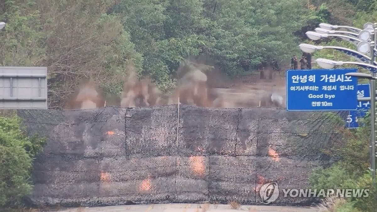 道路藍牌上還寫著「請走好」、「再見」等字樣，後面為北韓軍方進行爆破行動。（翻自《韓聯社》）
