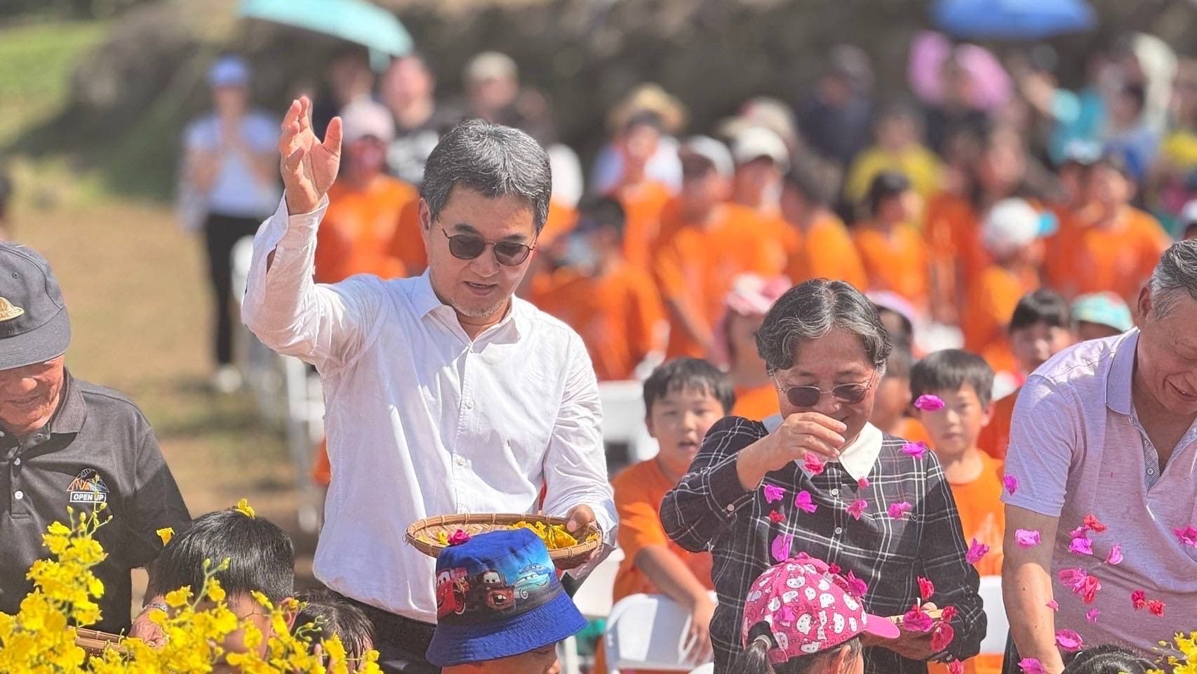 劉建國帶領民眾向天表達感謝之情，將花瓣灑向天際致敬。（華南社區提供）