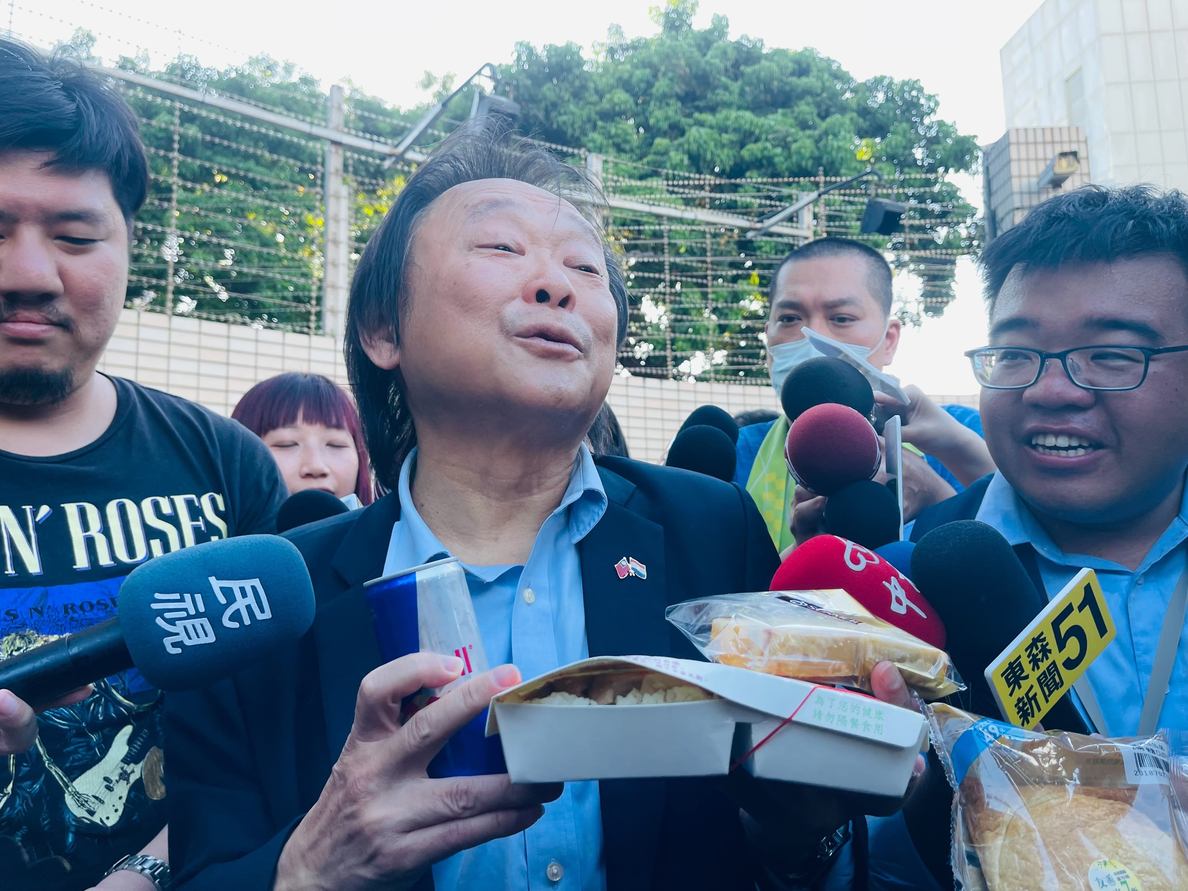 王世堅手持雞鴨便當、起酥蛋糕、能量飲料，還有要送給柯文哲室友的麵包。