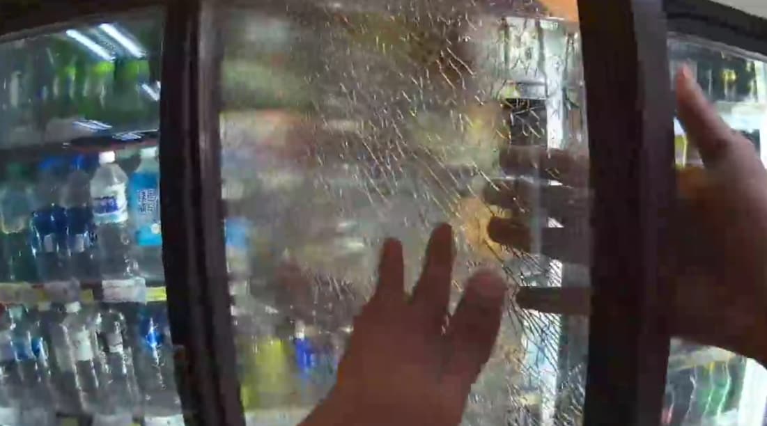 桃園一名裸男闖入超商後砸毀冰櫃玻璃門，隨後竟兀自坐在店外喝飲料。（翻攝畫面）